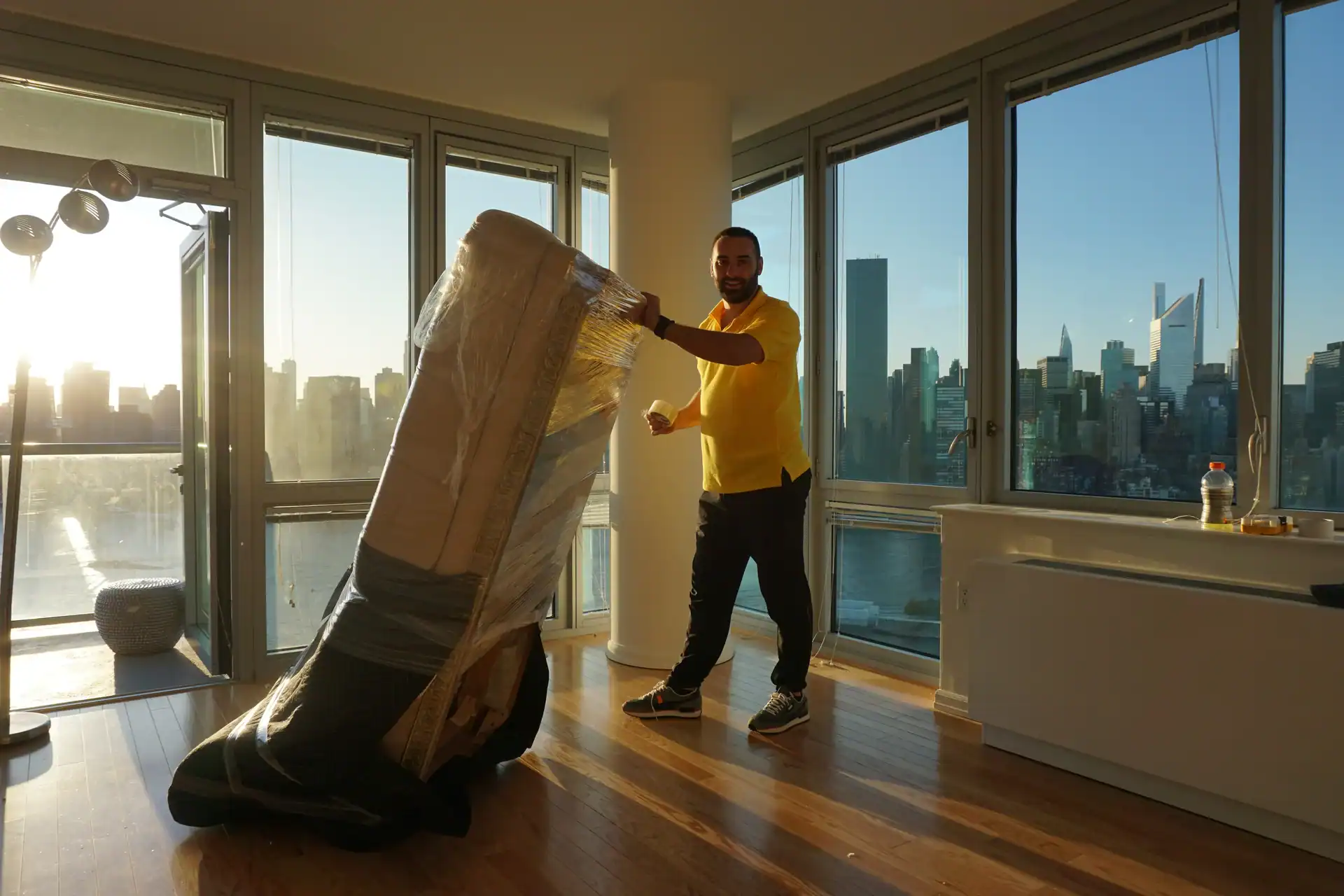 Mover carrying a wrapped sofa inside an apartment