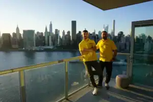 Movers standing on a rooftop with the Manhattan skyline behind them