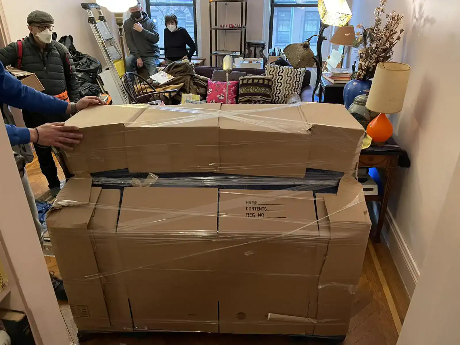 Movers wrapping a large wooden cabinet